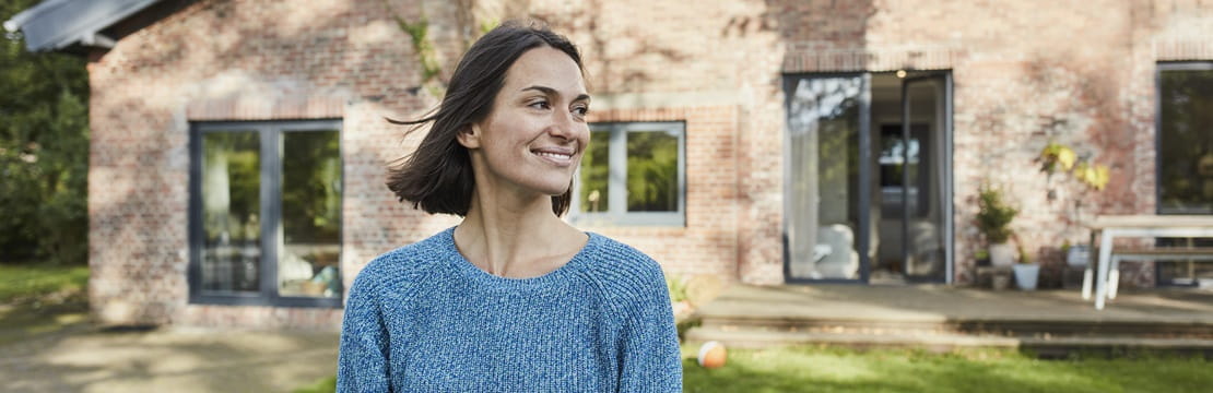 Smiling woman standing outside her home. 